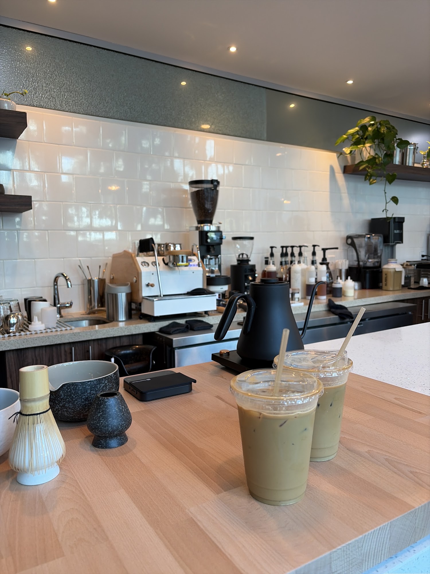 Chapola Cafe counter with iced green drinks, coffee equipment, and matcha whisk