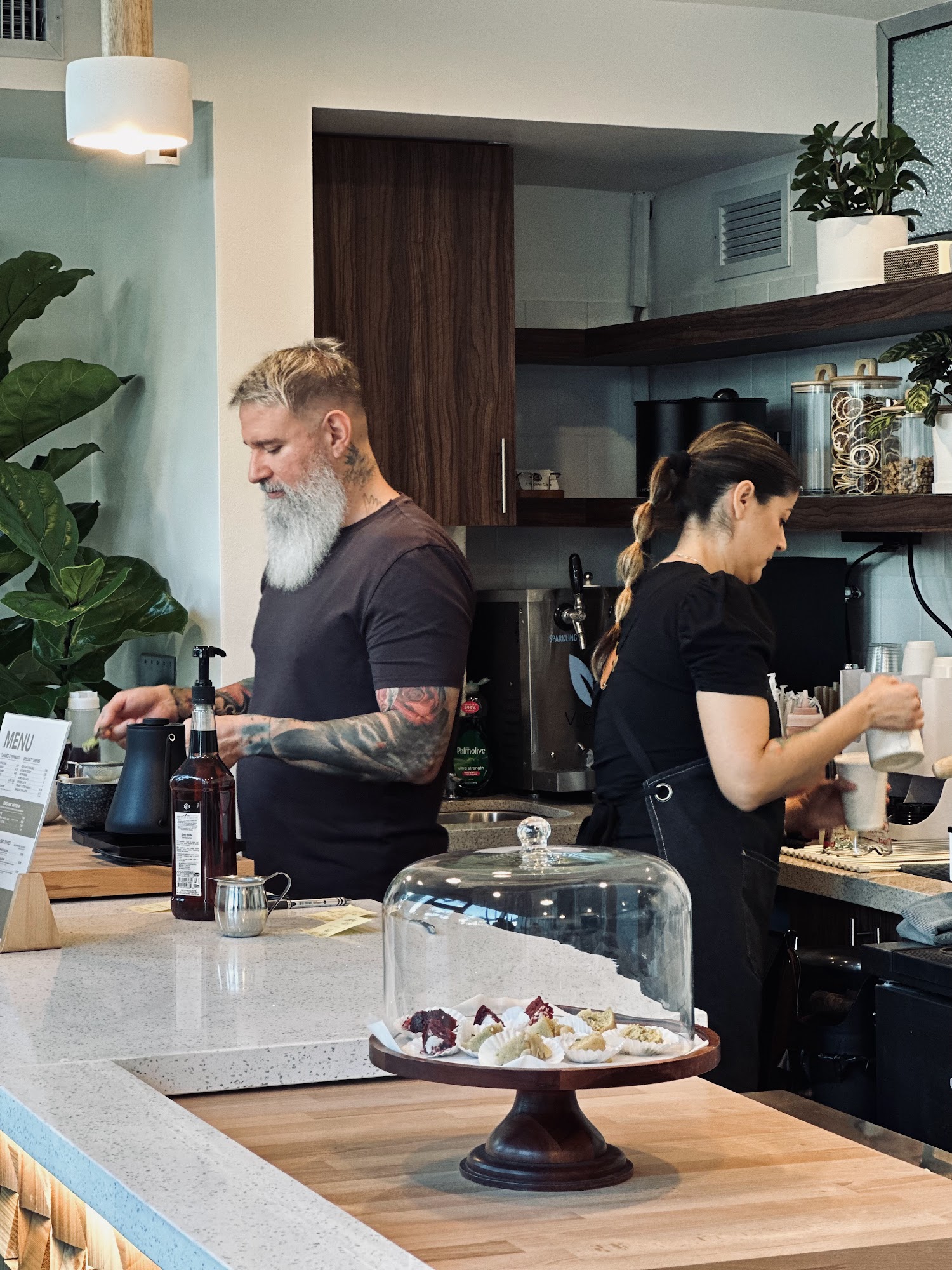 Chapola Cafe team working behind a counter with pastries and a menu sign